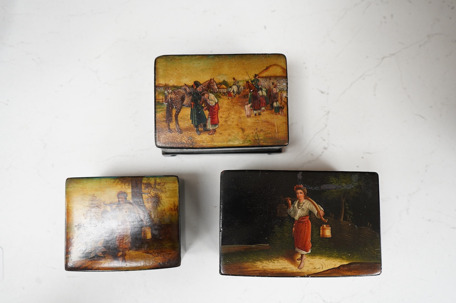 Three late 19th century Russian lacquer boxes, covers painted with Russian provincial scenes, largest14cm wide. Condition - varied